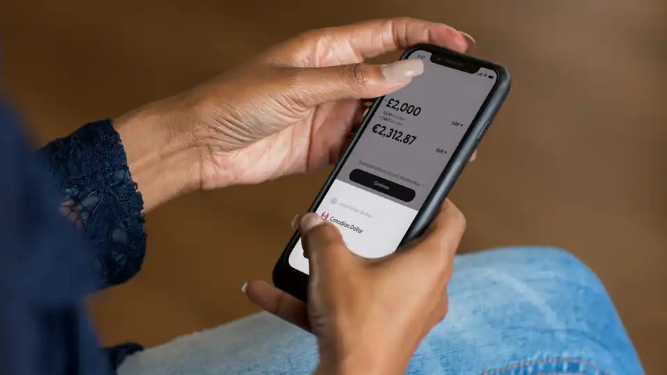 Mão segurando um celular com um aplicativo de finanças aberto