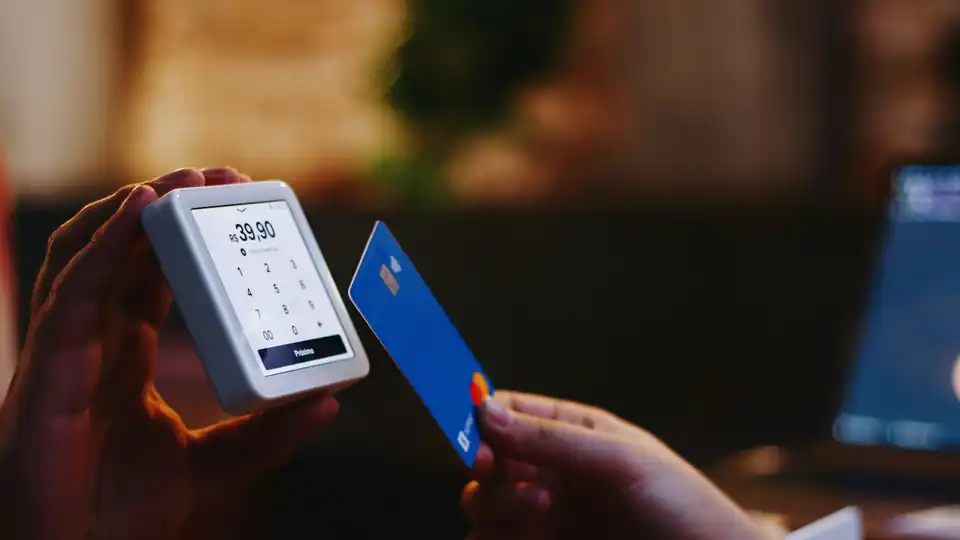 Pessoa segurando um cartão de pagamento e um celular