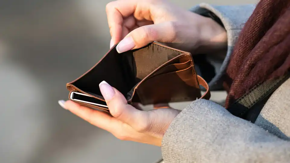 Mãos segurando uma carteira vazia e um celular